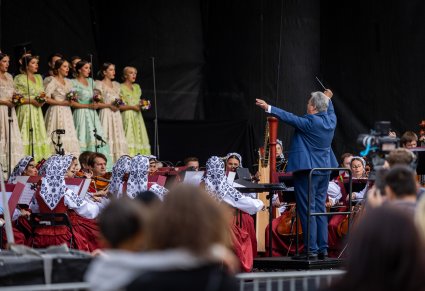 Na pierwszym planie Dyrektor Jacek Boniecki przed nim orkiestra i Artyści na scenie w kostiumach stylowych z końca XIX w.