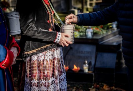 Zbliżenie na moment wrzucania datków do puszki Artystki w kostiumie wilanowskim na Starych Powązkach