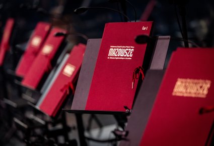 Zbliżenie na bordowe teczki na nuty ze złotym logotypem MAZOWSZE