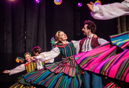 Pary Artystów w kostiumach opoczyńskich na scenie w trakcie wykonywania choreografii tanecznej