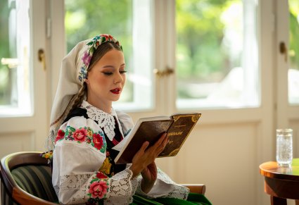 Zbliżenie na artystkę w kostiumie kocierzewskim, czytającą "Dziady"