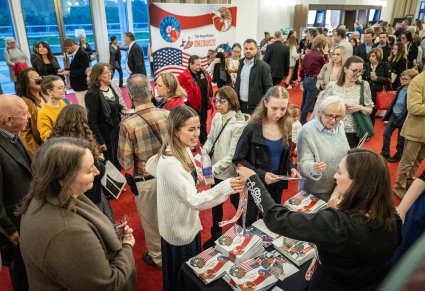 Grupa Publiczności koncertu w Kennedy Center w tle widoczna ścianka marketingowa z wydarzenia