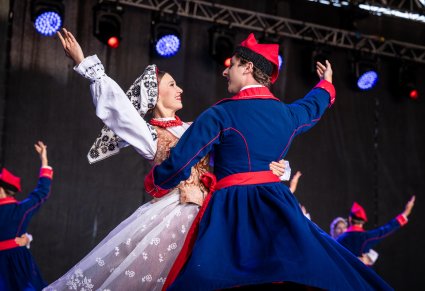 Na pierwszym planie para Artystów w kostiumach wilanowskich na scenie podczas wykonywania choreografii tanecznej