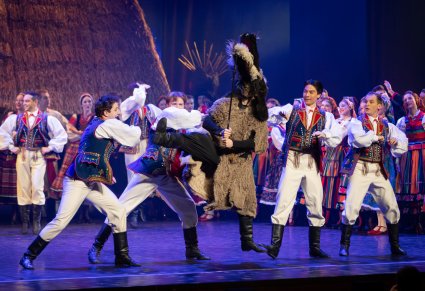 Artyści w kostiumach ludowych przy wspólnej scenie z postacią Turonia