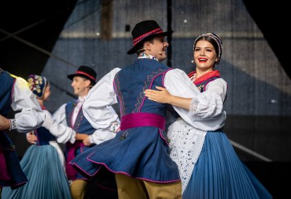 Pary Artystów w trakcie wykonywania choreografii tanecznej na scenie w kostiumach kaszubskich