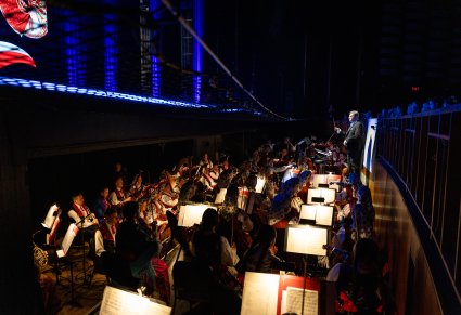 Widok na Orkiestron, Muzycy grający na instrumentach wraz z Dyrygentem