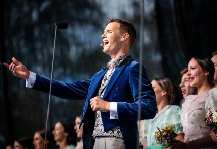 Solista na pierwszym planie a w tle Artystki w stylowych kostiumach