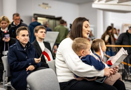 Zbliżenie na uczestników wspólnego śpiewania pieśni patriotycznym z zespołem "Mazowsze"