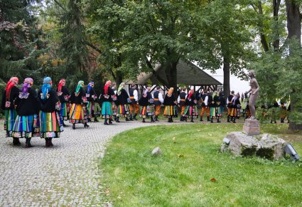 Artyści chóru w kostiumach łowickich idący na koncert