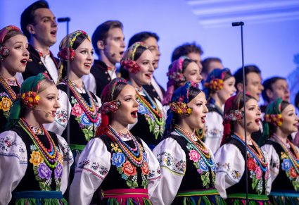 Zbliżenie na Artystów Chóru w kostiumach łowickich w trakcie śpiewu