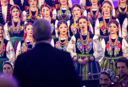 Zbliżenie na solistkę chóru podczas koncertu z widocznych chórem w tle