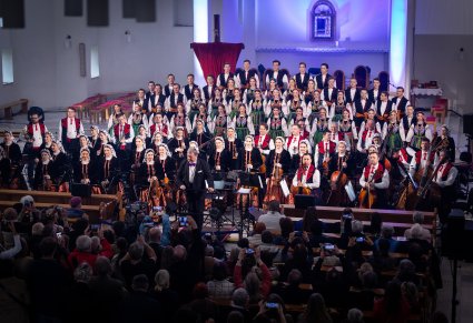 Chór, orkiestra i dyrygent podczas koncertu w kościele, widoczna widownia