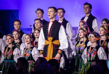 Zbliżenie na solistę chóru podczas koncertu z widocznych chórem w tle
