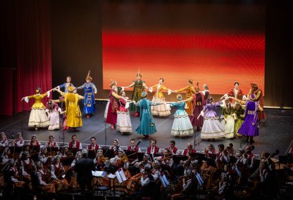 Na scenie Artyści Baletu w kontuszach w trakcie wykonywania choreografii tanecznej, niżej Artyści Orkiestry w kostiumach wilanowskich