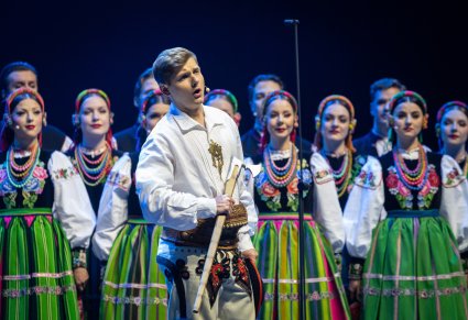 Zbliżenie na Solistę w kostiumie podhalańskich, za nim Artyści Chóru w kostiumach łowickich