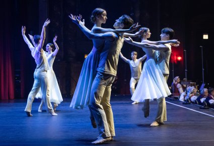 Na scenie Artyści w jasnych kostiumach współczesnych podczas wykonywania choreografii tanecznej