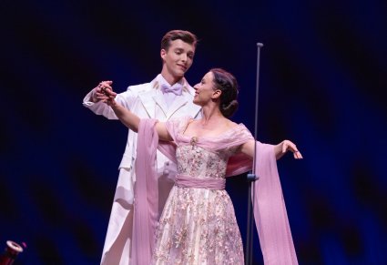 Solistka w długiej sukni wraz z tancerzem w trakcie wykonywania choreografii tanecznej