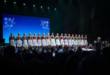 Na scenie Artystki chóru w kostiumach krakowskich w trakcie śpiewu, niżej Artyści Orkiestry w kostiumach wilanowskich wraz z Dyrygentem