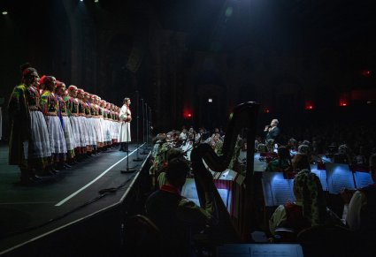 Widok na scenę z Artystami Chóru w kostiumach krakowskich oraz na członków orkiestry w kostiumach wilanowskich