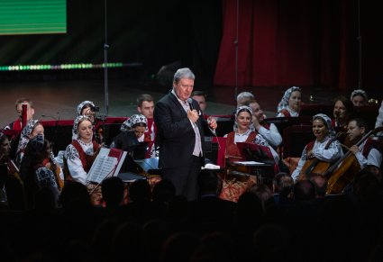 Dyrektor zespołu na tle członków Orkiestry w kostiumach wilanowskich