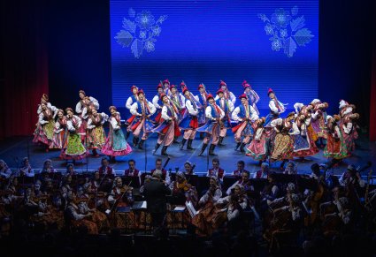 Na scenie Artyści w kostiumach krakowskich z widoczną niżej orkiestrą w kostiumach wilanowskich