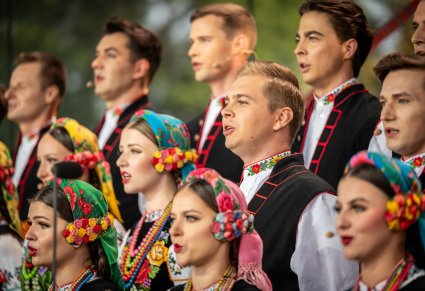 Zbliżenie na Artystów z chóru w kostiumach łowickich