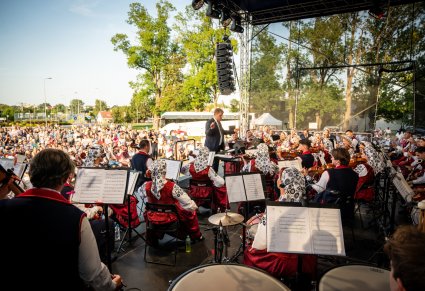Widok na Orkiestrę z Dyrektorem Jackiem Bonieckim, który dyryguje koncert. W tle widoczna publiczność