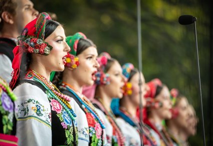 Zbliżenie na profile Artystek chóru w trakcie śpiewu. Artystki ubrane są w kostiumy łowickie