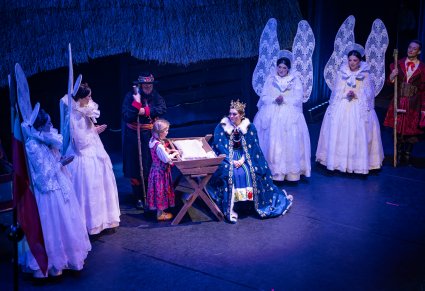 Przedstawienie świąteczne, nioły w bieli oraz królowa w niebieskim płaszczu z koroną, obok dziewczynka w ludowym stroju przy żłóbku