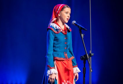 Śpiewająca uczestniczka gali na scenie w kostiumie kujawskim