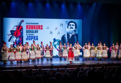 Uczestniczka gali a w tle chór zespołu "Mazowsze"