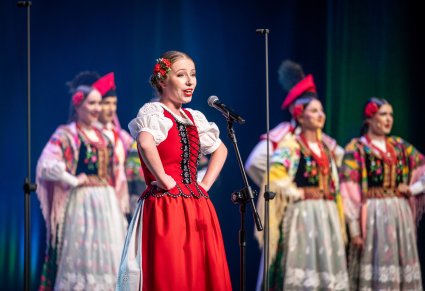 Uczestniczka gali a w tle chór zespołu "Mazowsze"