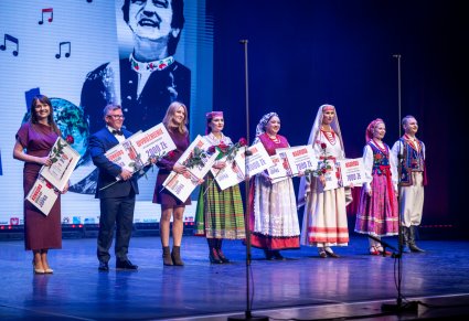 Uczestnicy Gali wraz z nagrodami na scenie i dwójka artystów z zespołu "Mazowsze" w kostiumie limanowskim