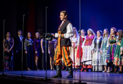 Solista w roli Furmana śpiewa a za nim stoją uczestnicy gali