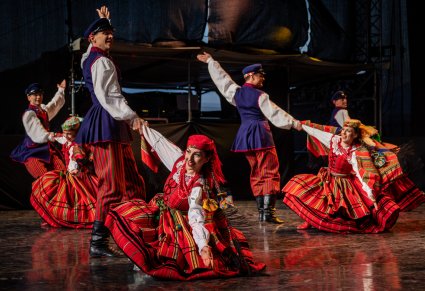 Trzy pary Artystów w kostiumach sieradzkich wykonujący choreografię taneczną na scenie