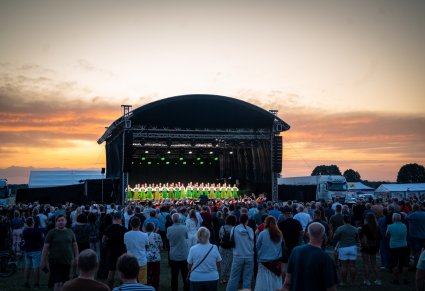 Widok na całą scenę, a na niej Artyści w kostiumach kurpiowskich, widoczna publiczność
