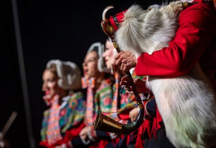 Na pierwszym planie instrument muzyczny a w tle 3 Artystki w kostiumach lubuskich na scenie