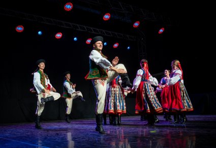 Artyści w kostiumach spiskich na scenie wykonujący choreografię taneczną