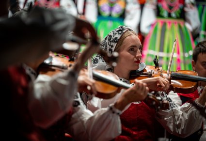 Na pierwszym planie zbliżenie na skrzypaczki a w tle widoczne Artystki w kostiumach łowickich