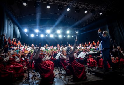 Na pierwszym planie orkiestra z Dyrygentem Jackiem Bonieckim a w tle artyści w kostiumach ludowych na scenie