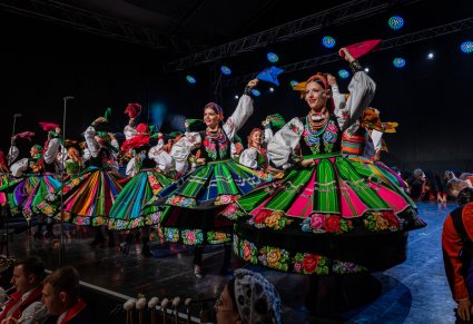 Artystki w kostiumach łowickich na scenie w trakcie wykonywania choreografii tanecznej