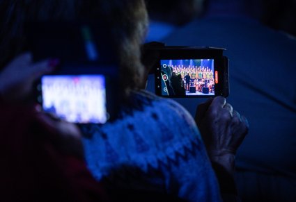 Zbliżenie na telefon, na którym ktoś z publiczności nagrywa fragment koncertu