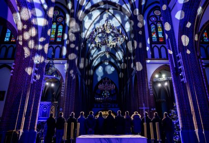 Szeroki kadr w którym widać chór od tyłu oraz sklepienie katedry z efektami świetlnymi