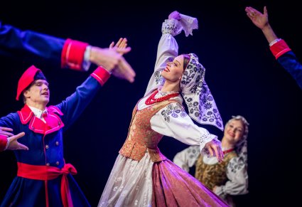 Artystka zespołu Mazowsze w kostiumie wilanowskim tańczy na scenie trzymając w dłoni chusteczkę