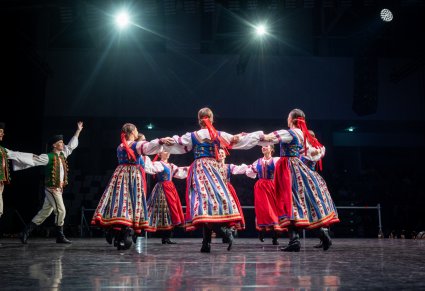 Artyści zespołu Mazowsze w kostiumach spiskich tańczą na scenie tworząc koło