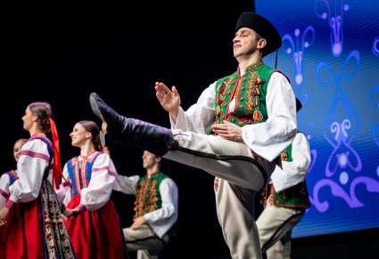 Tancerz zespołu Mazowsze w kostiumie spiskim tańczy na scenie, ma uniesioną nogę