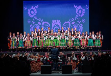 Chórzyści zespołu Mazowsze w kostiumach łowickich śpiewają na scenie