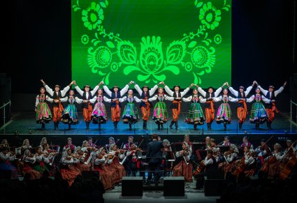 Artyści w kostiumach łowickich tańczą na scenie