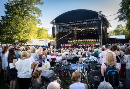 Widownia podczas koncertu, w tle widoczna scena i chór