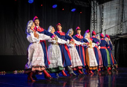 Grupa tancerzy w kostiumach wilanowskich w trakcie tańca na scenie